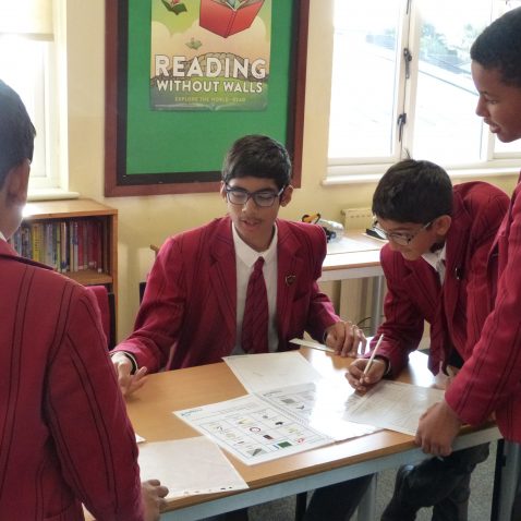 group of students leaning over a desk