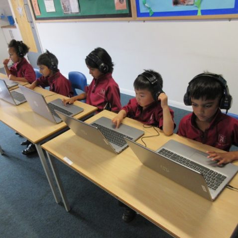 5 children in a row working on their laptops