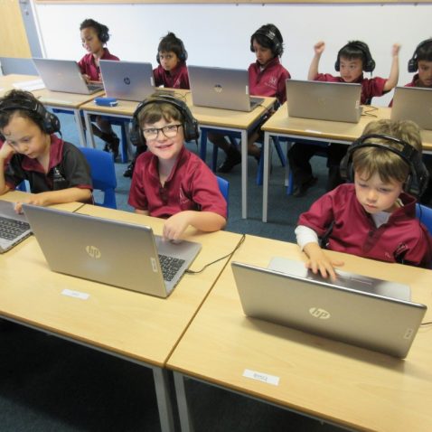 Smiling children getting to use laptops