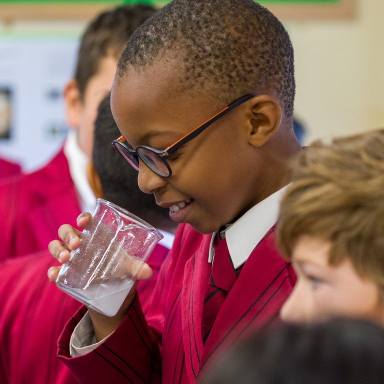 Student looking into the glass containing solution in the science lab