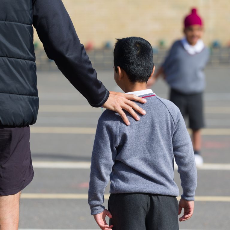 teacher with hand on child's shoulder