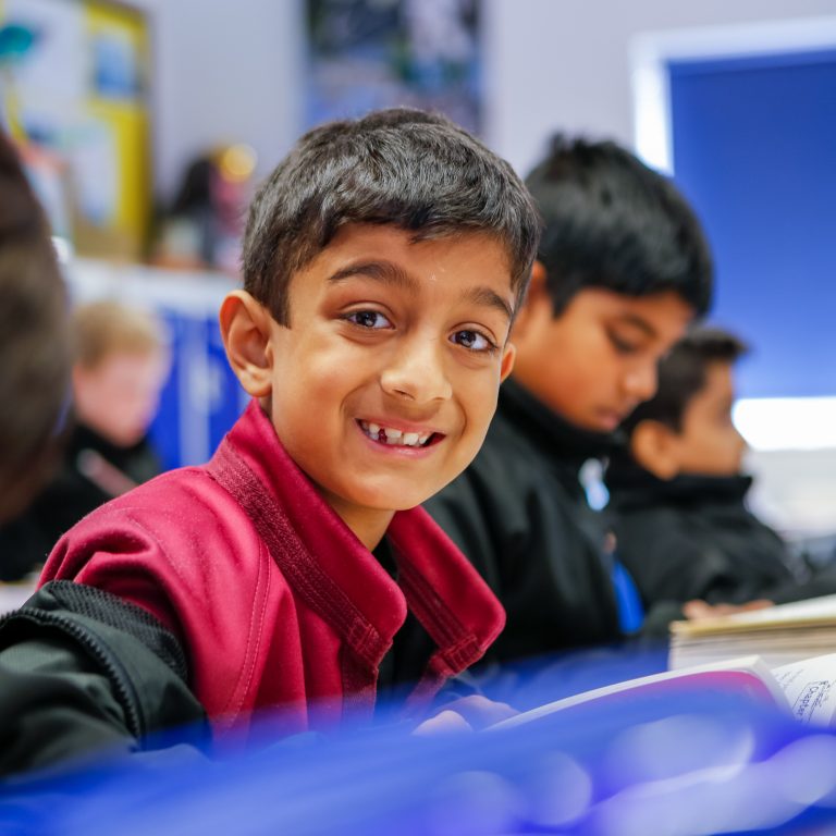 Student in class smiling as they all read books