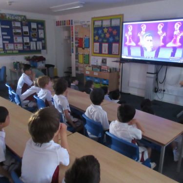 group of school boys watching interactive screen in classroom