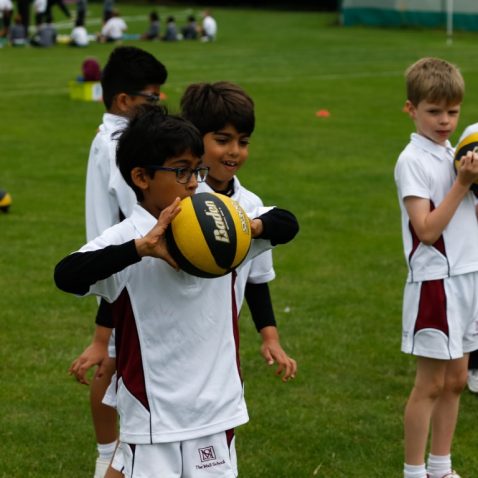 children wearing PE kit, holding netballs