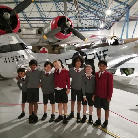 group of school boys standing in front on an aeroplane