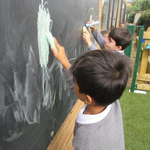 two school boys drawing on chalk board