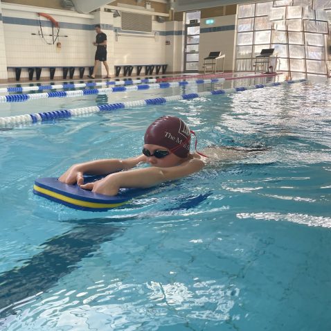 Student using a float to direct themselves in the swimming pool