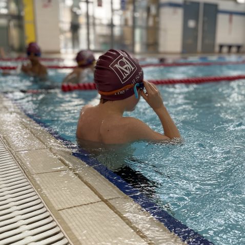 Student adjusting their goggles in the swimming pool