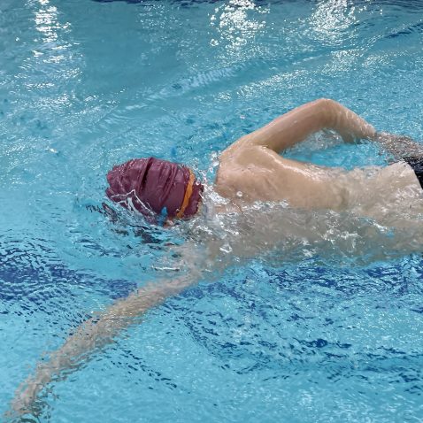 Front crawl being performed by a student int he swimming pool