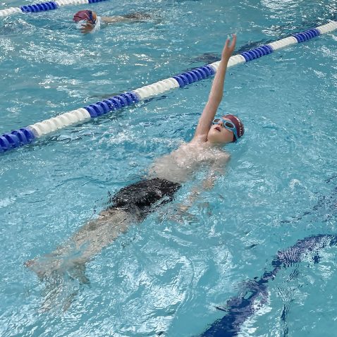 Child performing back stroke in the swimming pool