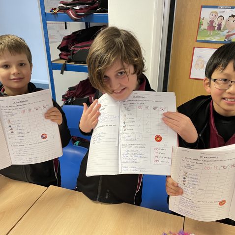 children holding their exercise books up