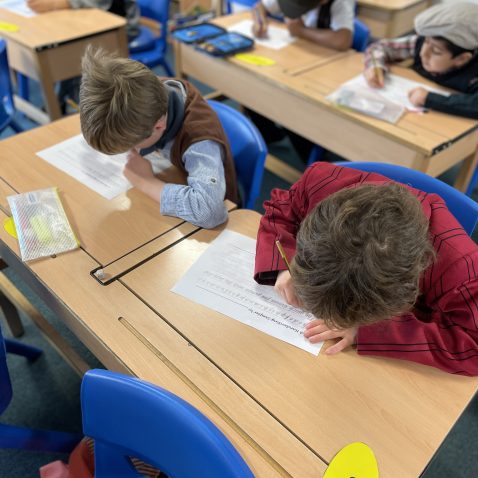 2 students writing down onto a piece of paper