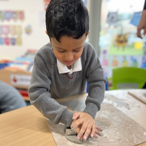 student making clay shapes