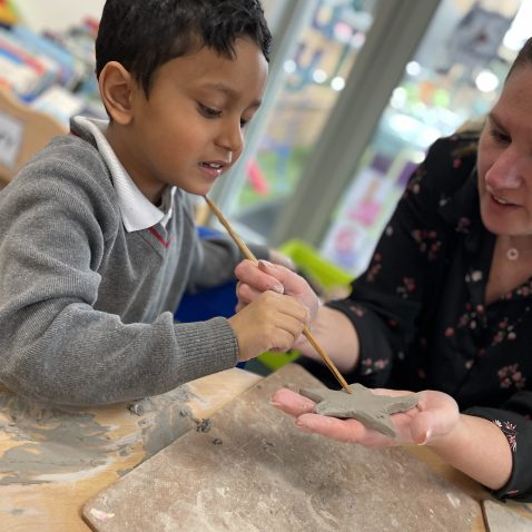 student making clay shapes