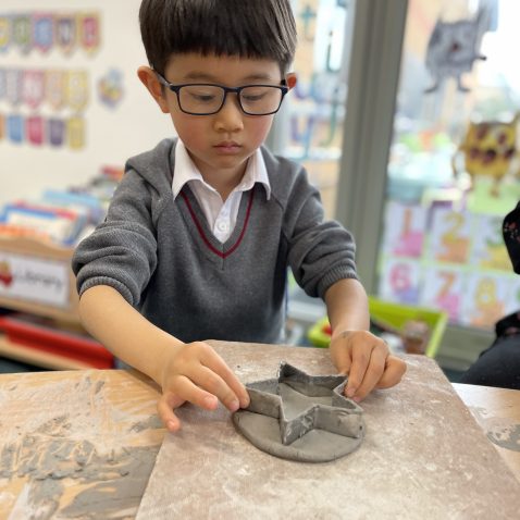student making clay shapes