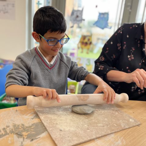 student rolling clay