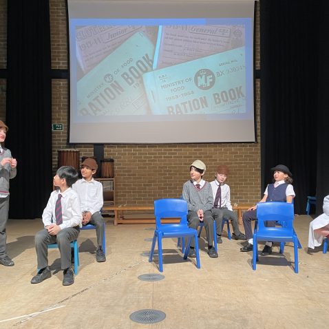 children sat on chairs in front of a screen