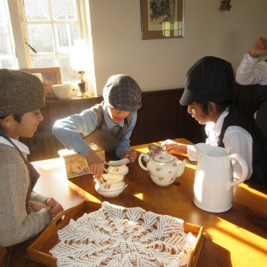 students dressed in period clothes pouring tea