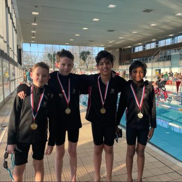 children wearing medals stood in a swimming pool