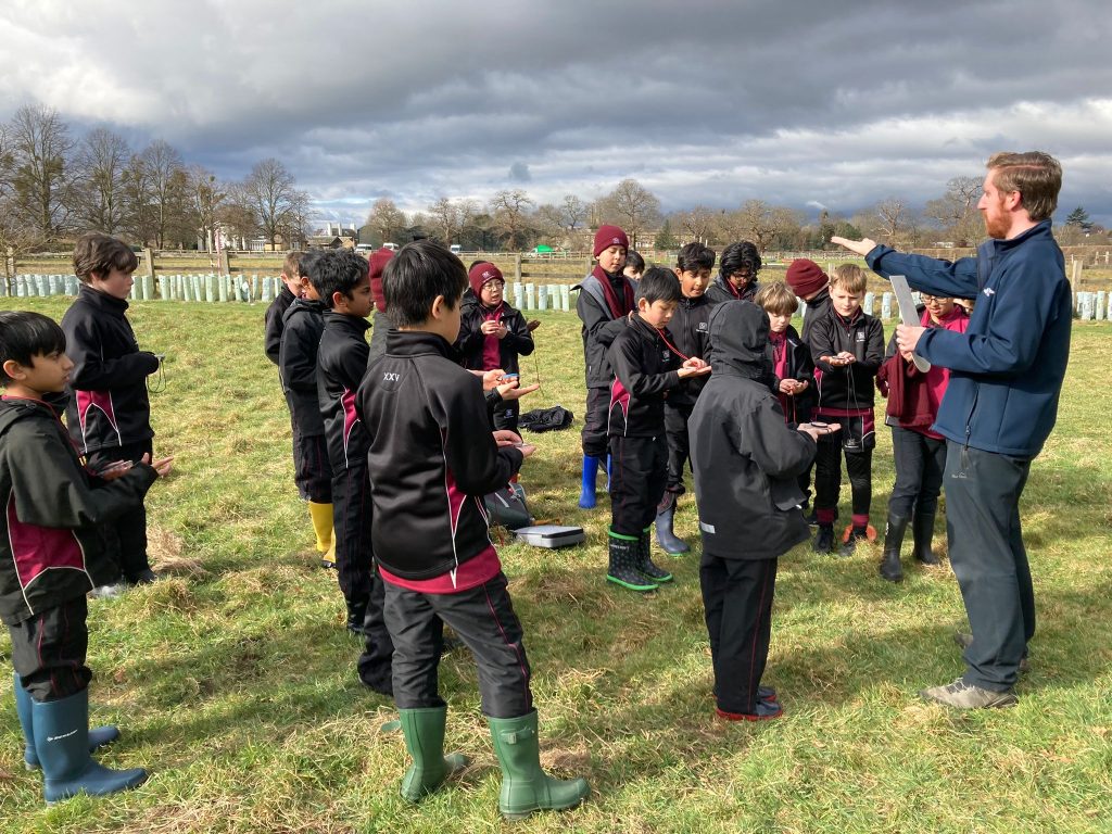 students and teachers out on a field looking at their wooden tools