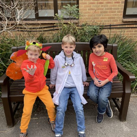 3 students dressed up and sat on a bench