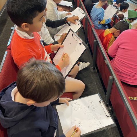 students drawing onto their pieces of paper, attached to a clipboard