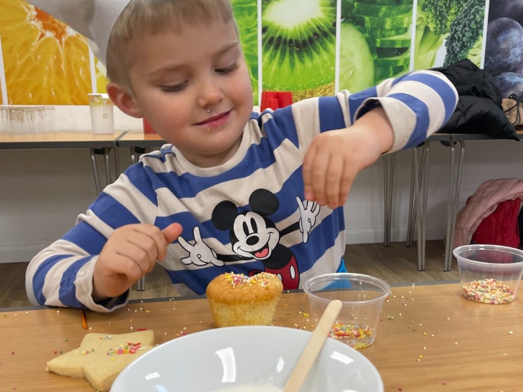 a student layering a cupcake with his own toppings
