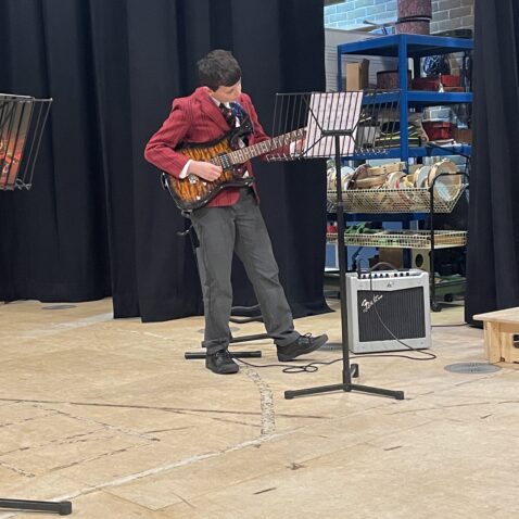Schoolboy soloist is playing guitar in the Theatre