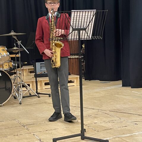 Soloist playing saxophone in Theatre, with a black curtain as a backdrop
