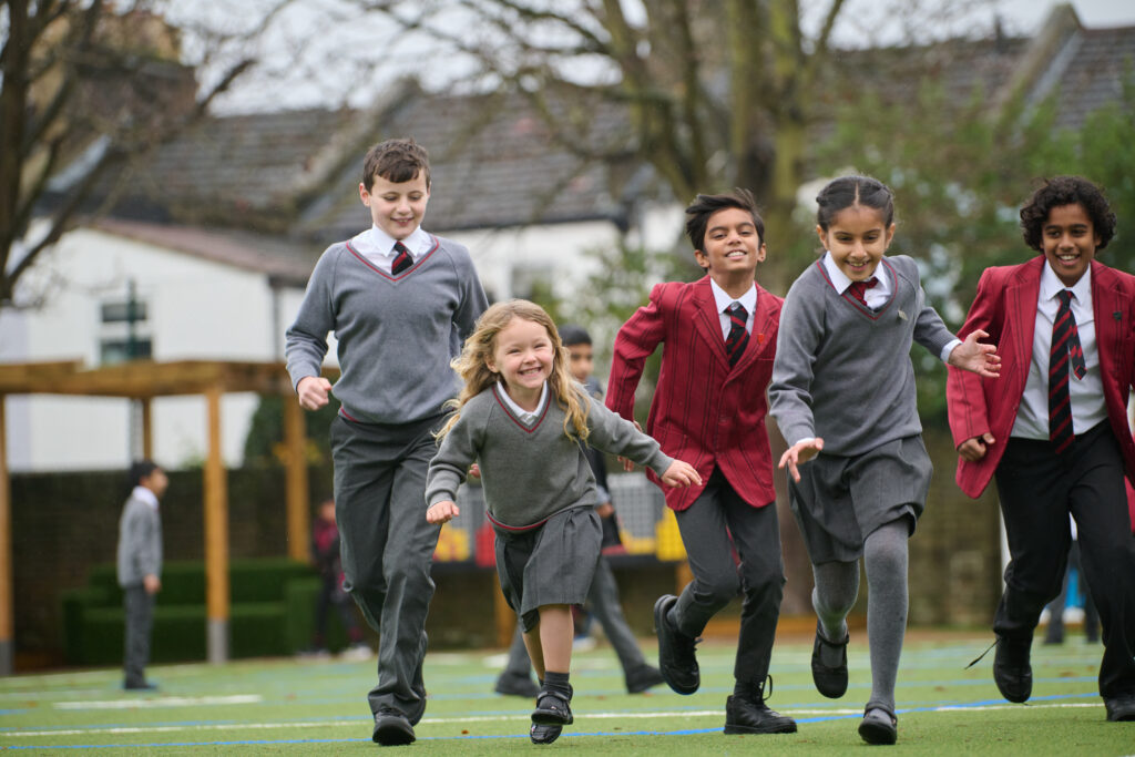 Mixed schoolchildren running through the playground towards the camera