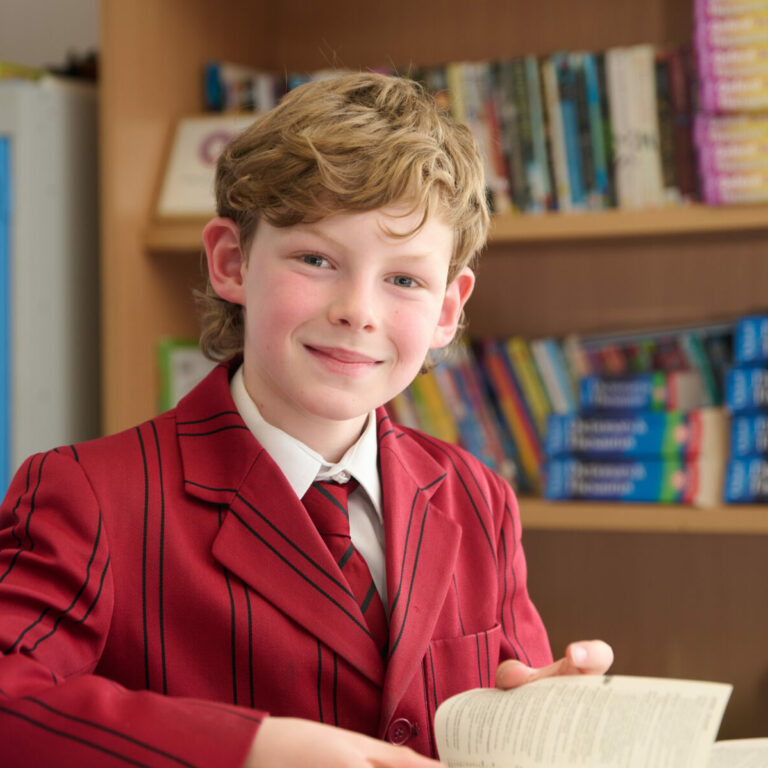 Smiling schoolboy in library, with books in the background