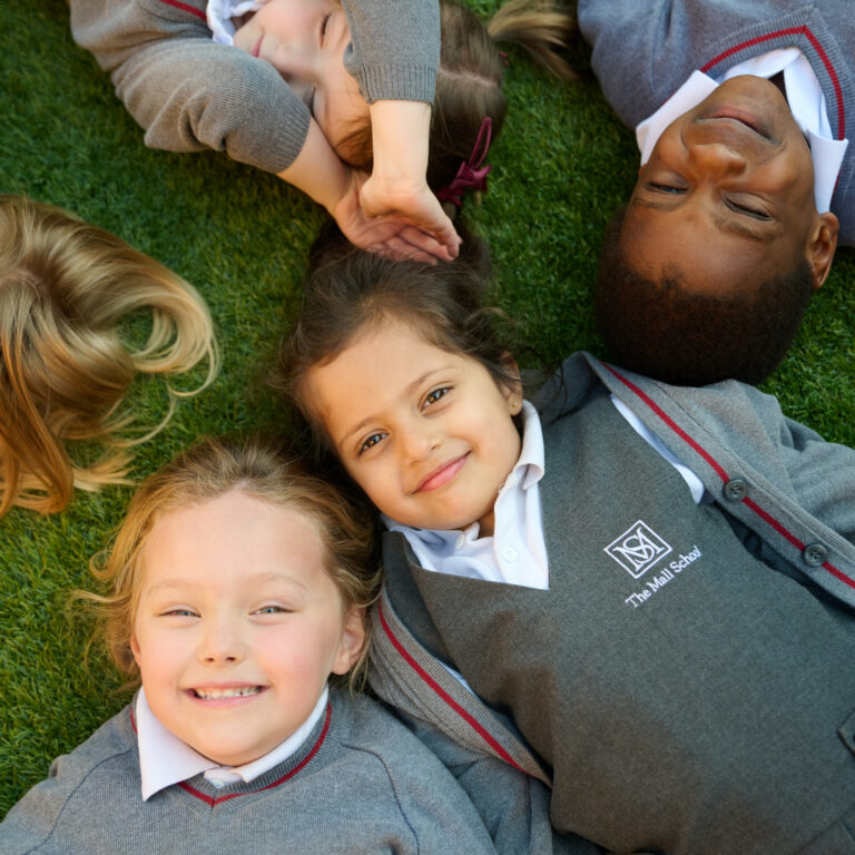 Group of children lying on the grass, looking at the camera and smiling