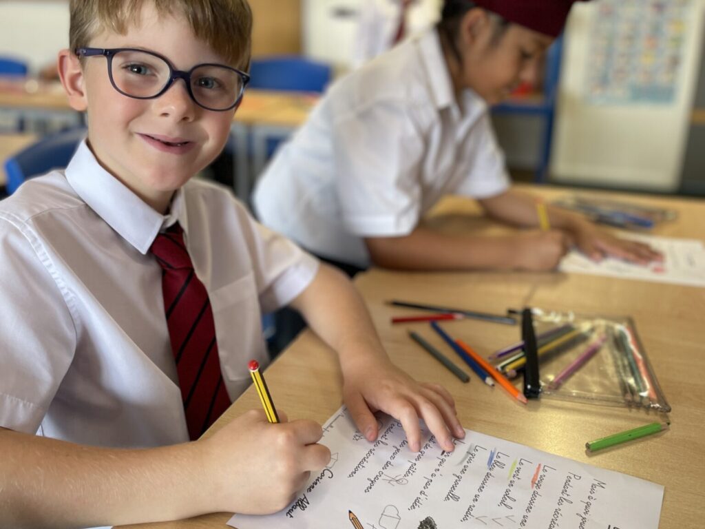 Schoolboy in classroom, writing a poem at his desk
