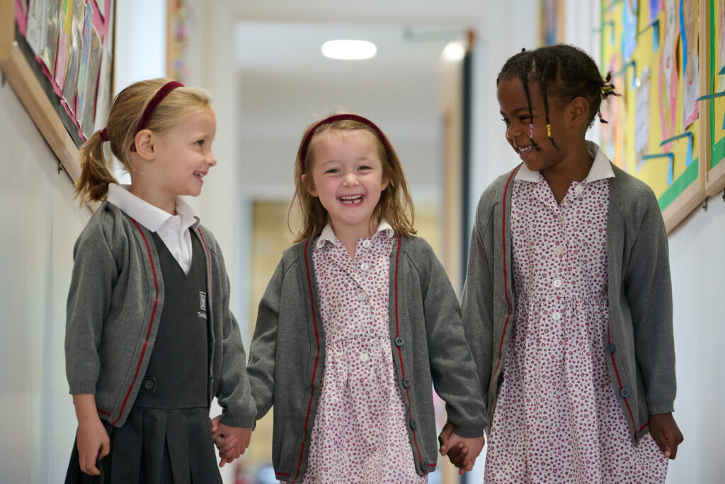 Three girls in their Mall School uniform, smiling and happy