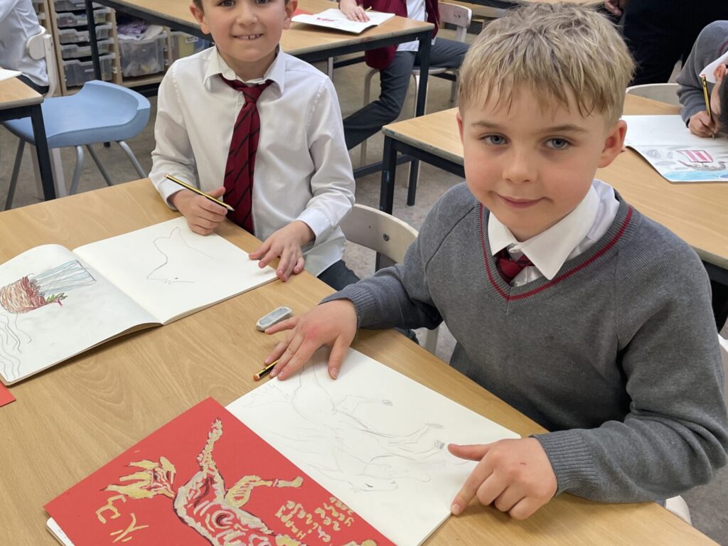 Two schoolboys in the Art studio, with gold-painted fire horses, drawn on red paper, to celebrate Lunar New Year
