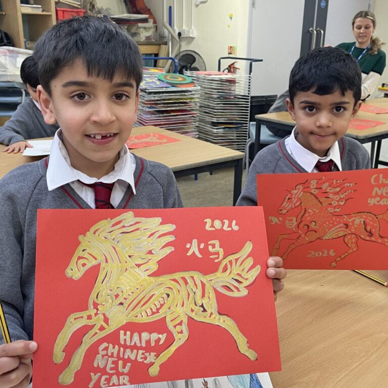 Two schoolboys holding up their fire horse drawings, to commemorate Lunar New Year