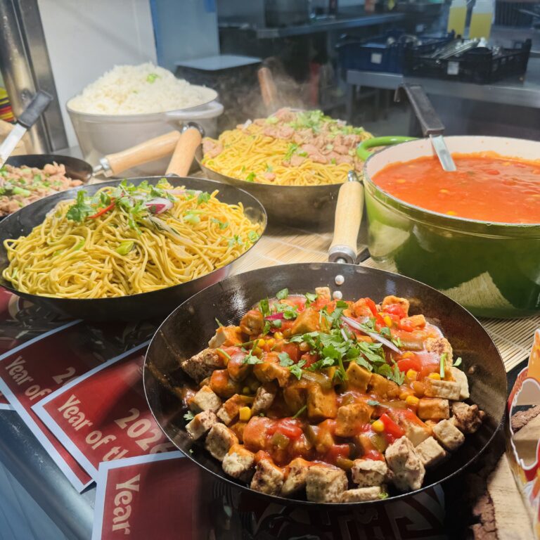 Delicious lunch display including noodles, rice, sweet and sour chicken and stir-fried vegetables for Lunar New Year