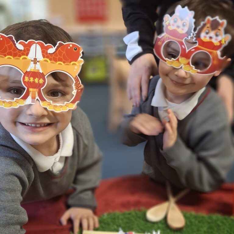 Twin boys in Reception classroom, wearing Lunar New Year paper glasses